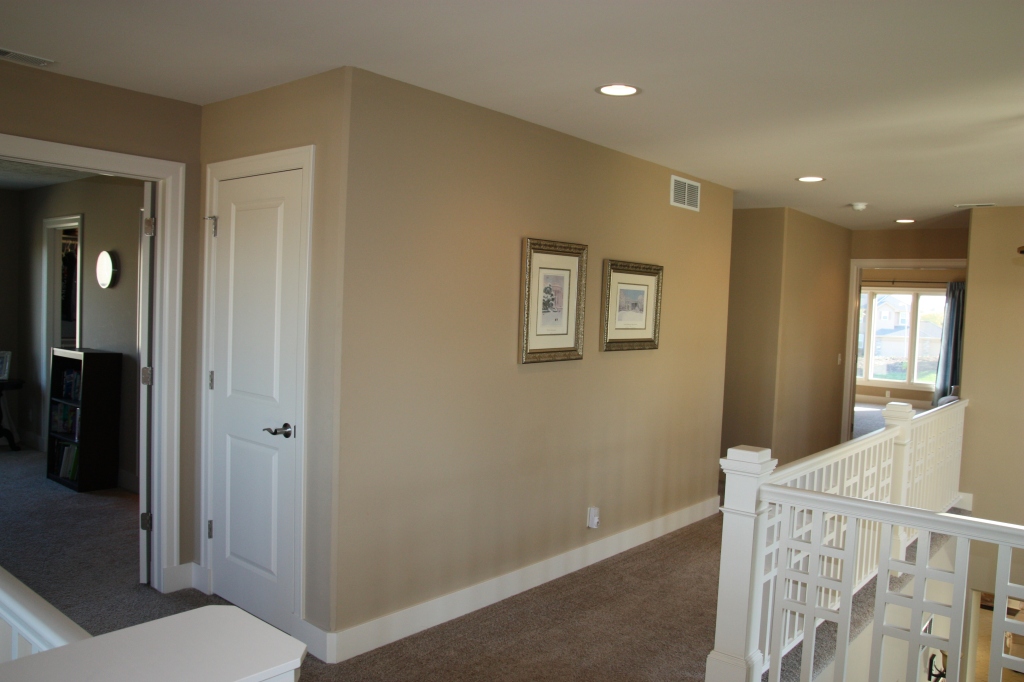 A hallway with a staircase off to the side and off white walls.